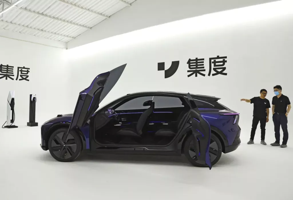 A-black-car-sits-against-a-white-backdrop-decorated-with-chinese-writing-the-cars-doors-are-open-like-a-butterflys-wings-tw